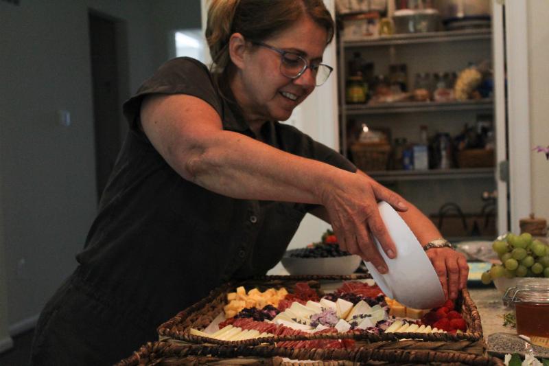Delicately placing fruits onto the board is one small step in preparing Burkholder’s Fig and Brie Charcuterie boards.